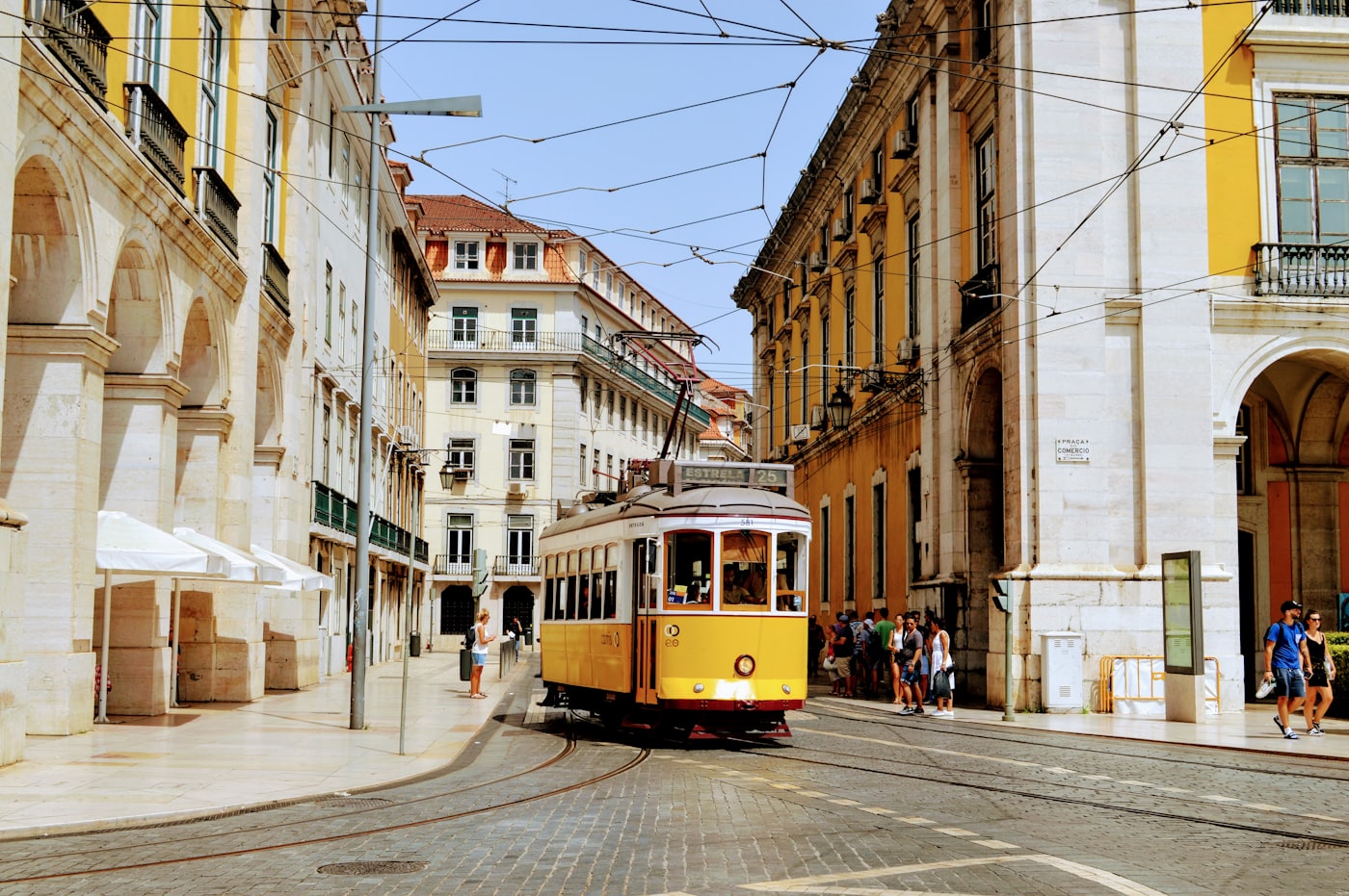 A yellow tram turning through a square in central Lisbon