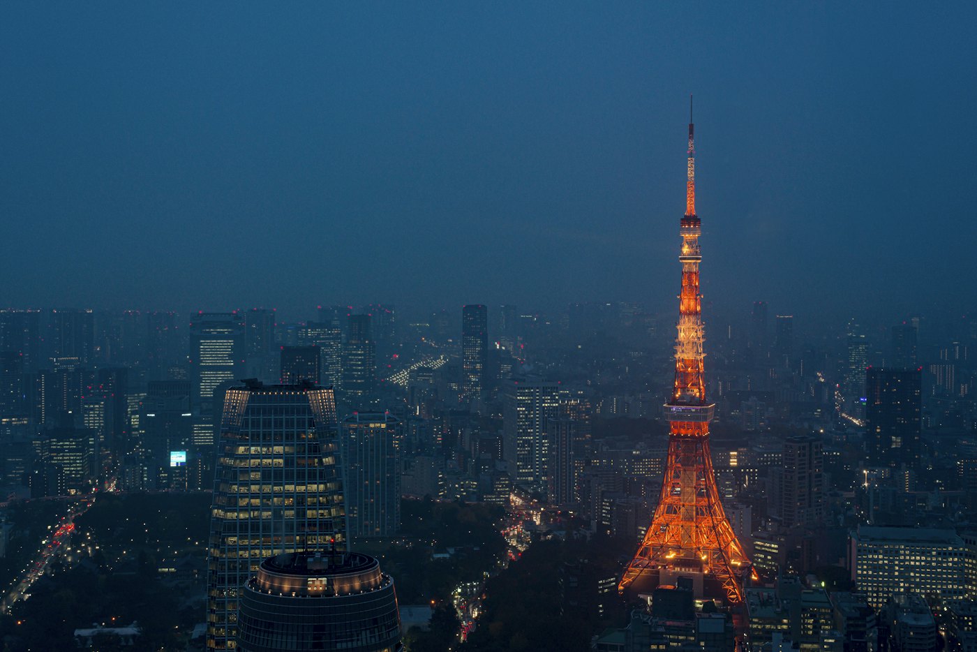 Tokyo Tower lit orange above the Minato skyline at dusk